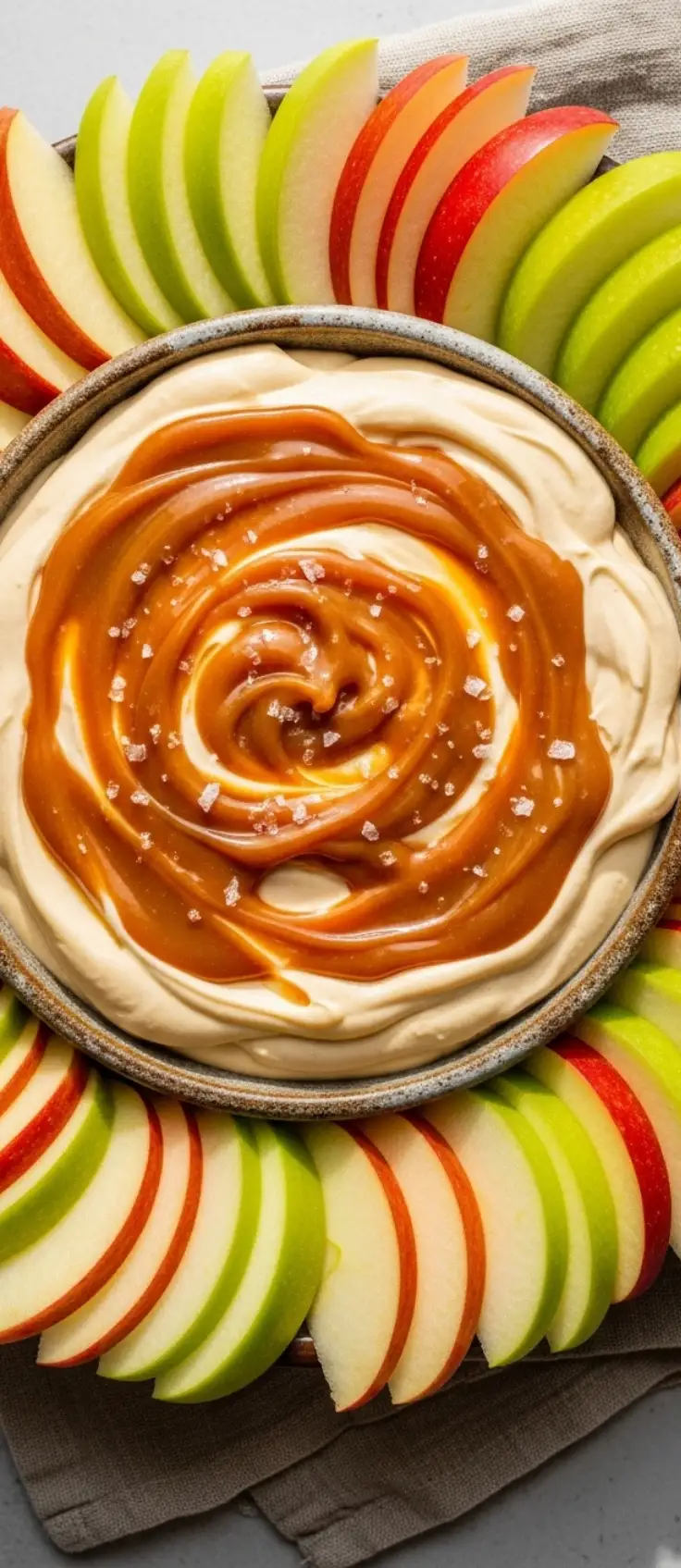 Overhead shot of caramel cheesecake dip with green and red apples