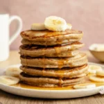 Fluffy banana oat pancakes stacked and topped with banana slices