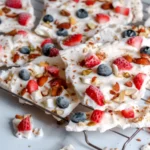 Frozen yogurt bites stacked with berries spilling beside them